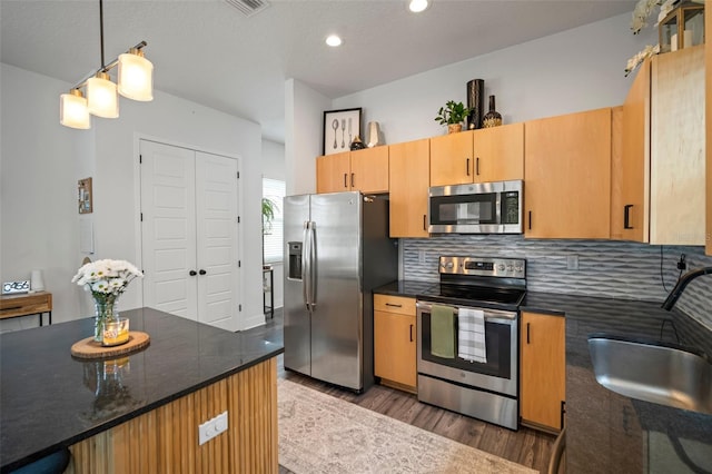 kitchen featuring tasteful backsplash, wood finished floors, a sink, stainless steel appliances, and recessed lighting