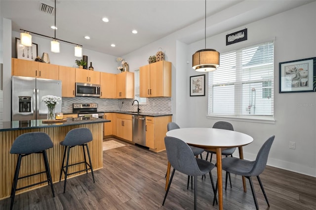 kitchen featuring dark countertops, stainless steel appliances, decorative backsplash, dark wood-type flooring, and visible vents