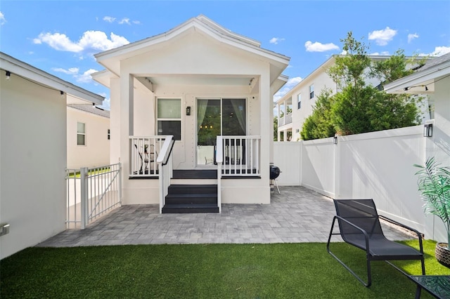 rear view of property with a lawn, a fenced backyard, a patio area, and stucco siding