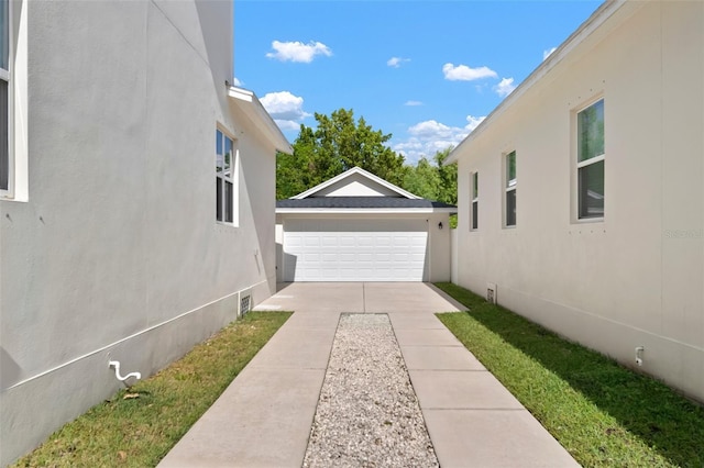 view of side of home with a garage, an outbuilding, and stucco siding