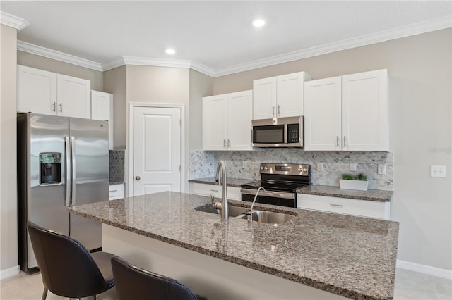 kitchen featuring a sink, appliances with stainless steel finishes, white cabinets, and a breakfast bar