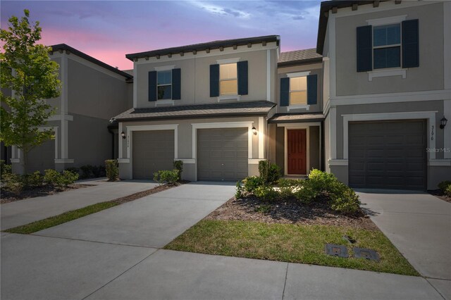 view of front facade with concrete driveway, an attached garage, stucco siding, and a shingled roof