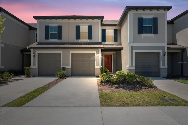 view of front of home featuring concrete driveway, stucco siding, and a garage
