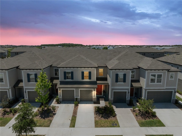 view of property featuring stucco siding, driveway, a residential view, and a garage