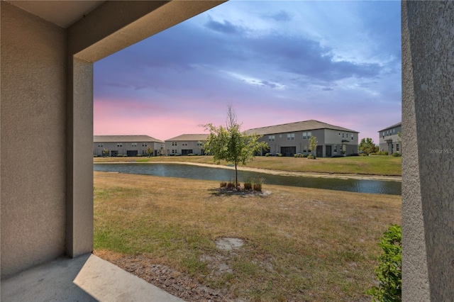 yard at dusk featuring a water view and a residential view