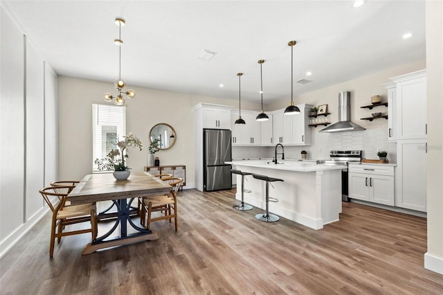 121 E Warren Ave Unit 1, Tampa, FL 33602 - kitchen featuring wall chimney range hood, stainless steel appliances, light countertops, wood finished floors, and recessed lighting
