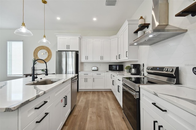 121 E Warren Ave Unit 1, Tampa, FL 33602 - kitchen with wall chimney exhaust hood, stainless steel appliances, light wood-type flooring, white cabinets, and recessed lighting