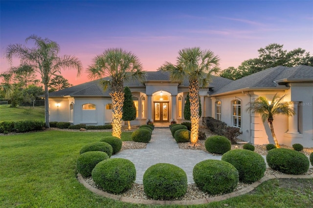 mediterranean / spanish-style home featuring a front lawn, stucco siding, and french doors
