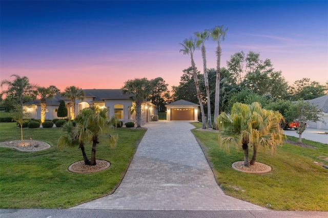 view of front of home featuring an outbuilding, stucco siding, a yard, and driveway