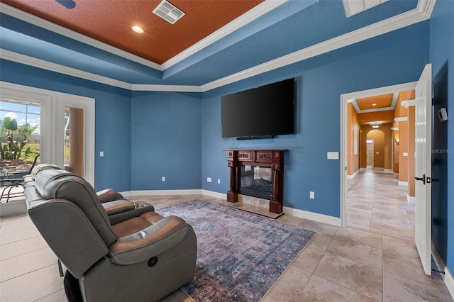 living area featuring visible vents, crown molding, baseboards, a raised ceiling, and a premium fireplace
