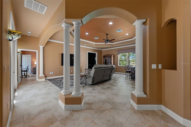 living area featuring visible vents, a ceiling fan, decorative columns, and arched walkways