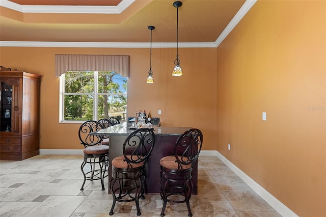 dining area featuring crown molding, baseboards, bar area, and a raised ceiling