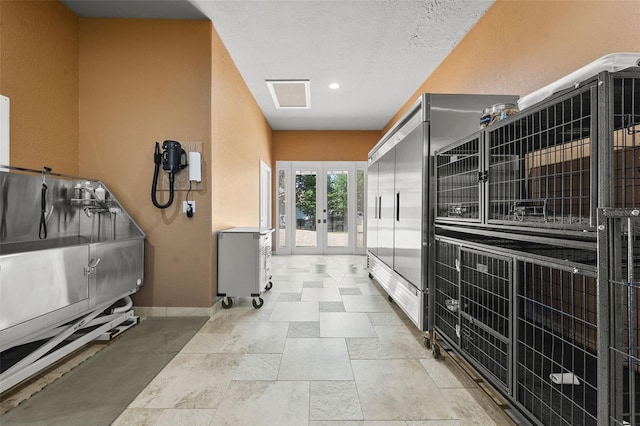 hallway with baseboards, visible vents, and french doors