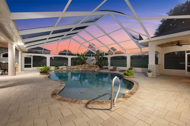 outdoor pool with a patio, a ceiling fan, and glass enclosure