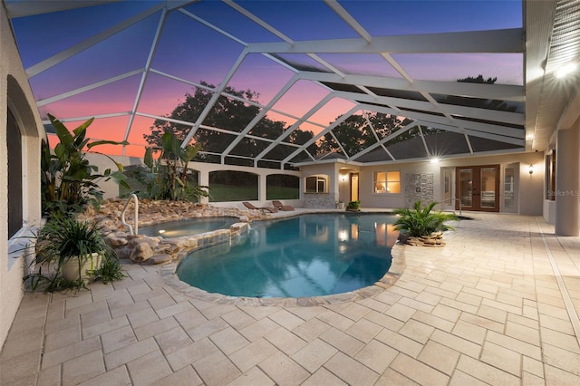 view of swimming pool with french doors, a lanai, a pool with connected hot tub, and a patio area