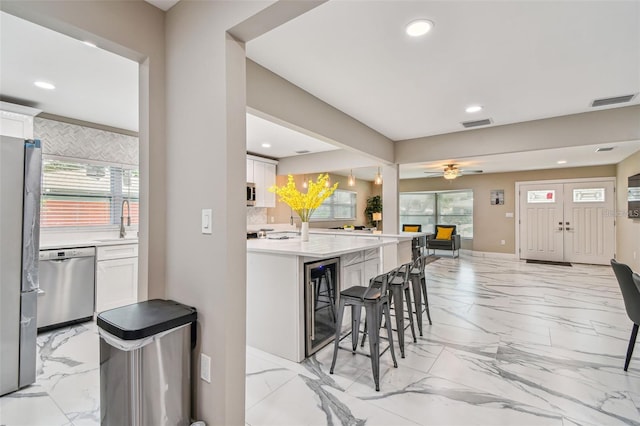 2042 Craft Ln, Sarasota, FL 34239 - kitchen with marble finish floor, a breakfast bar, recessed lighting, white cabinets, and appliances with stainless steel finishes