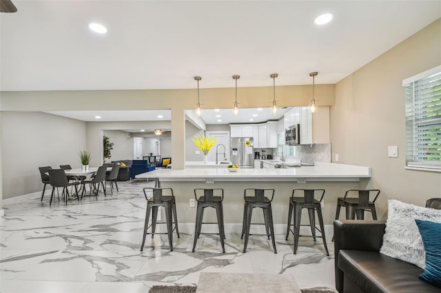 2042 Craft Ln, Sarasota, FL 34239 - kitchen with marble finish floor, a peninsula, a breakfast bar, light countertops, and stainless steel appliances