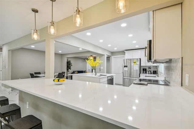 2042 Craft Ln, Sarasota, FL 34239 - kitchen with a peninsula, a kitchen island with sink, a kitchen bar, tasteful backsplash, and stainless steel appliances