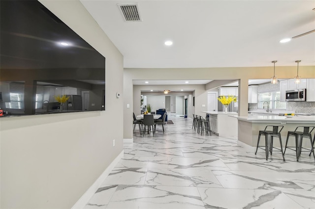2042 Craft Ln, Sarasota, FL 34239 - kitchen featuring visible vents, a breakfast bar, baseboards, light countertops, and stainless steel microwave