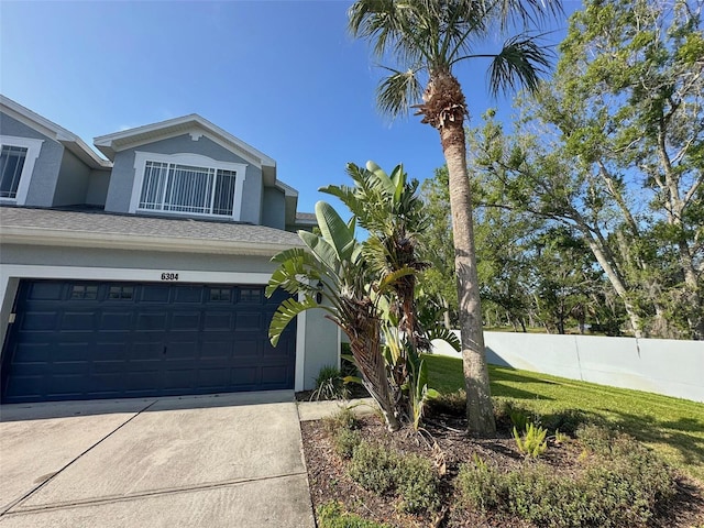 view of front facade with fence, stucco siding, driveway, and a garage