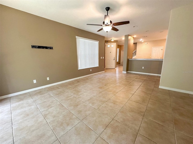 empty room with baseboards, a ceiling fan, and light tile patterned floors