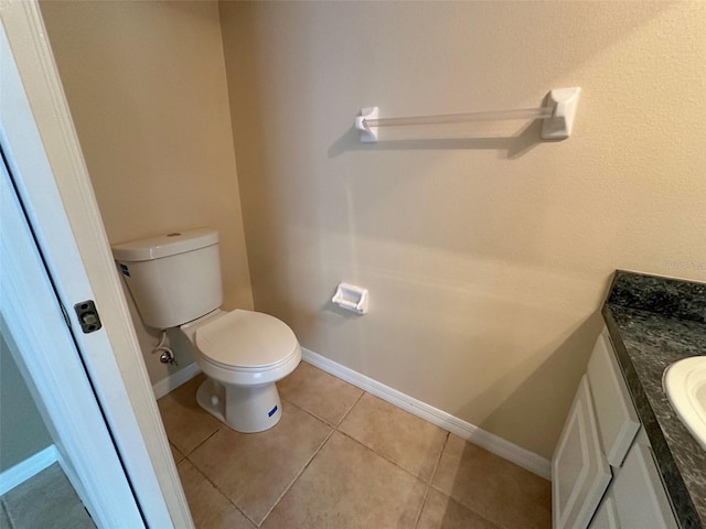 half bathroom featuring baseboards, tile patterned flooring, toilet, and vanity