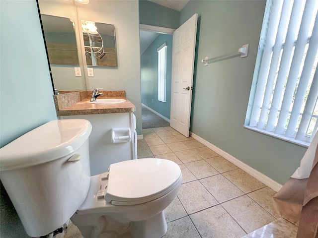 bathroom with toilet, baseboards, a sink, and tile patterned flooring