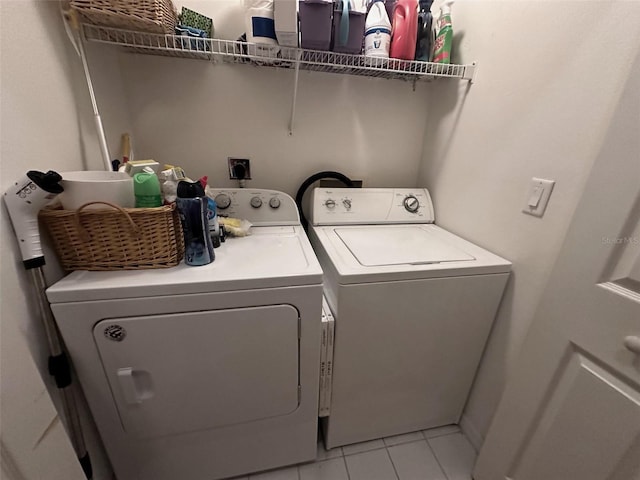 clothes washing area featuring light tile patterned floors and washer and dryer