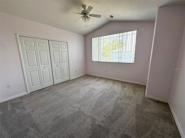 unfurnished bedroom featuring carpet flooring, a textured ceiling, and vaulted ceiling