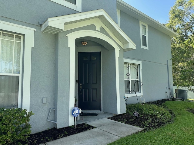 view of exterior entry featuring central AC and stucco siding