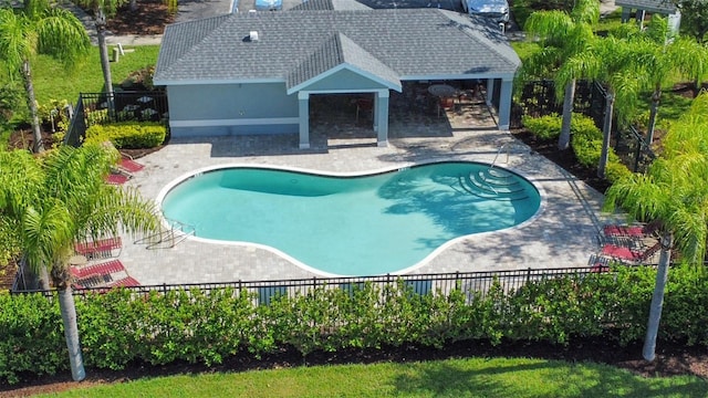 community pool with a fenced backyard and a patio area