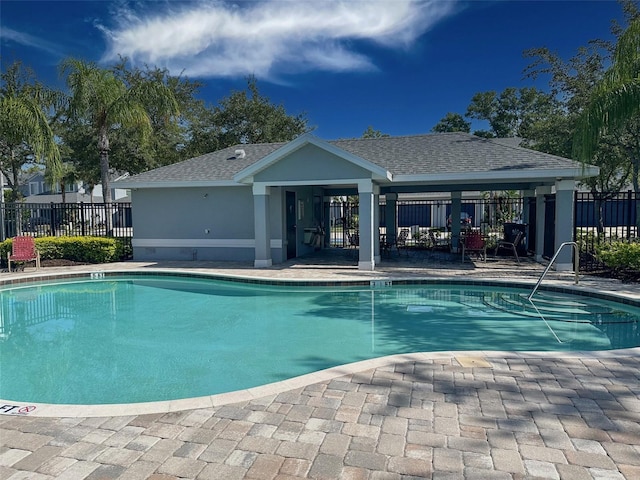 pool with a patio area and fence