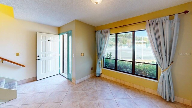 tiled entryway featuring a textured ceiling and baseboards