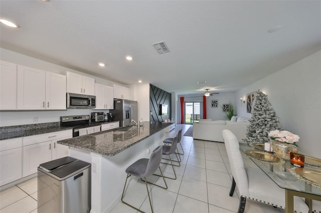 kitchen with visible vents, appliances with stainless steel finishes, a sink, open floor plan, and a breakfast bar