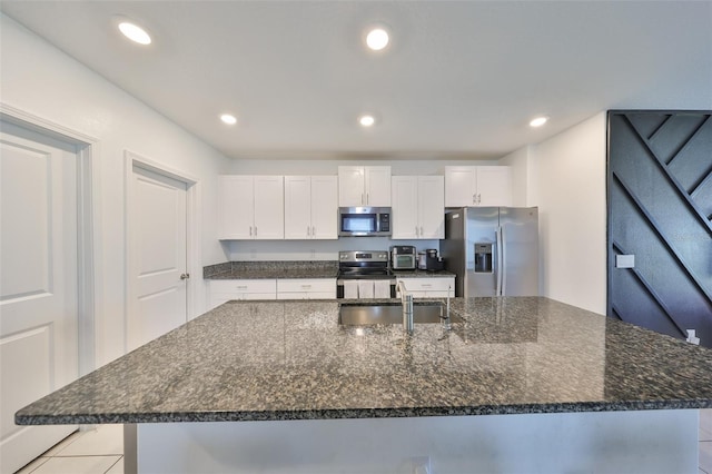 kitchen featuring a sink, appliances with stainless steel finishes, white cabinets, and a large island