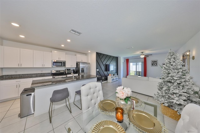 kitchen with visible vents, light tile patterned flooring, white cabinetry, dark stone countertops, and appliances with stainless steel finishes