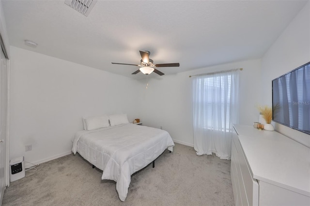 bedroom featuring a ceiling fan, baseboards, visible vents, and light carpet