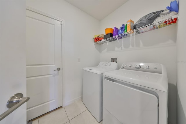washroom featuring baseboards, laundry area, light tile patterned flooring, and washing machine and clothes dryer