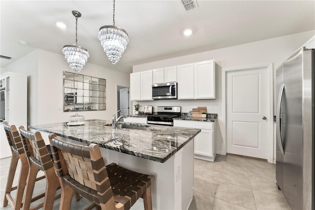 35780 Sunflower Hill Dr, Zephyrhills, FL 33541 - kitchen featuring appliances with stainless steel finishes, an inviting chandelier, a sink, dark stone counters, and visible vents