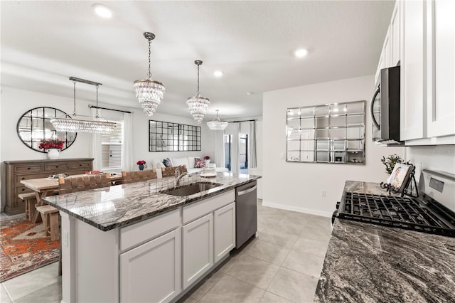 35780 Sunflower Hill Dr, Zephyrhills, FL 33541 - kitchen featuring appliances with stainless steel finishes, a sink, stone countertops, an island with sink, and white cabinetry