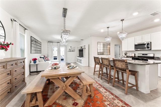 35780 Sunflower Hill Dr, Zephyrhills, FL 33541 - kitchen with visible vents, a breakfast bar, an island with sink, appliances with stainless steel finishes, and a notable chandelier