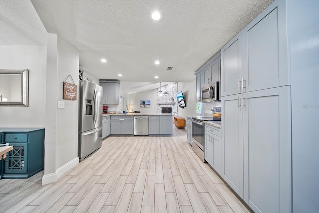kitchen featuring a peninsula, light wood-type flooring, light countertops, baseboards, and appliances with stainless steel finishes