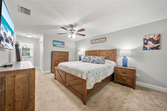 bedroom featuring baseboards, a textured ceiling, visible vents, and light colored carpet