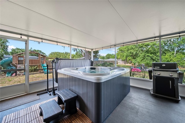 exterior space featuring a hot tub, fence, a playground, and area for grilling