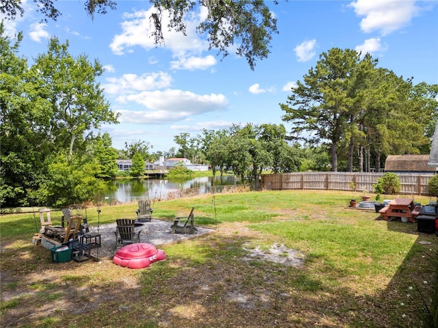 view of yard with a water view, a fire pit, and fence