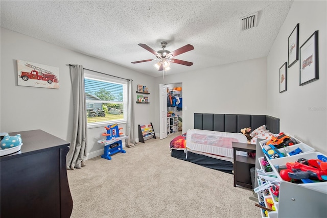 carpeted bedroom with visible vents, ceiling fan, and a textured ceiling