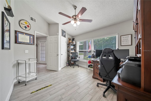 office space featuring vaulted ceiling, a textured ceiling, visible vents, and a ceiling fan
