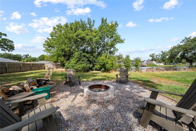 view of yard featuring fence, a water view, and a fire pit