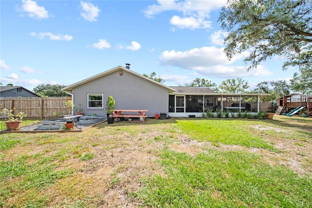 rear view of property featuring fence, a lawn, a sunroom, a playground, and a vegetable garden