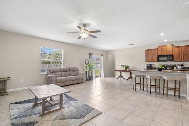 6708 Hazelnut Spice Dr, Ruskin, FL 33573 - living room with ceiling fan, a textured ceiling, visible vents, light tile patterned floors, and baseboards
